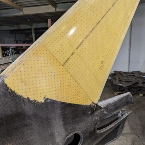 A yellow and black plane wing in an industrial setting.