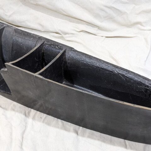 A black canoe sitting on top of a white sheet.